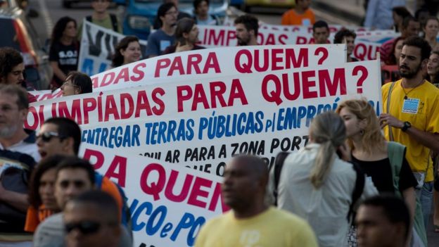 Manifestantes com cartaz dizendo 