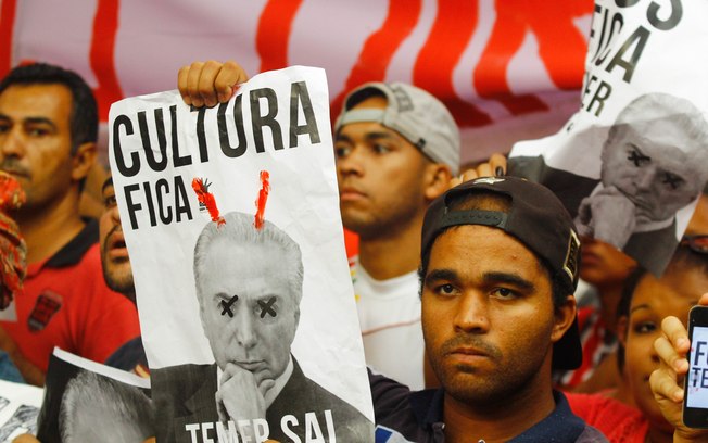 Manifestantes erguem faixas criticando medidas da primeira semana do governo do peemedebista