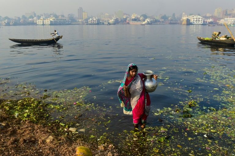 Bengalesa recolhe água de lago poluído em Daca