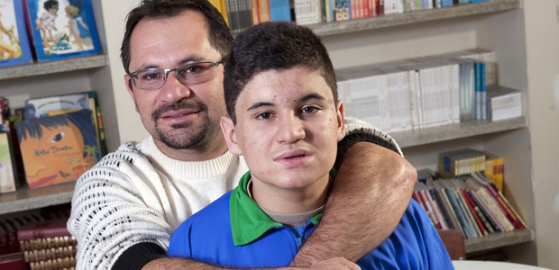 Matheus Santana da Silva, aluno autista, com seu pai na biblioteca da escola. Foto: Marcelo Min